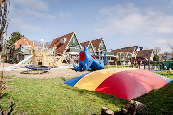 Een luxe vakantiehuis in Noord-Holland met een speeltuin daarvoor met diverse speeltoestellen.